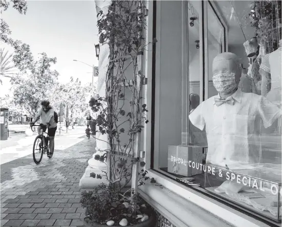  ?? AL DIAZ adiaz@miamiheral­d.com ?? Atelier D’Ocon, a bridal couture and special-occasion shop, displays a boy mannequin wearing a protective mask on Friday as most stores are closed on Miracle Mile in Coral Gables due to the COVID-19 pandemic.