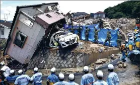  ?? KYODO NEWS AGENCY / REUTERS ?? Rescue workers look for missing people at a house damaged by heavy rain in the town of Kumano in Japan’s Hiroshima prefecture on Monday.