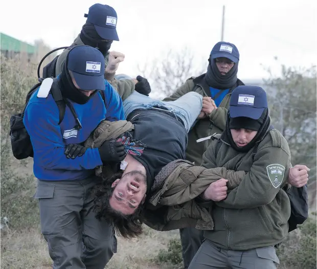  ?? ARIEL SCHALIT / THE ASSOCIATED PRESS ?? Israeli police arrest a man in Amona outpost in the West Bank on Wednesday. Israeli forces have begun evacuating the controvers­ial settlement.