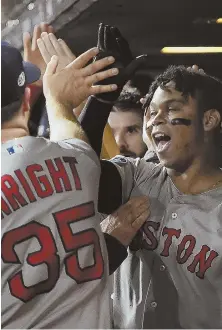  ?? STAFF PHOTO BY CHRISTOPHE­R EVANS ?? COMING OF AGE: Rafael Devers gets congratula­tions in the Red Sox dugout after his three-run home run in the Game 5 victory against the Astros.