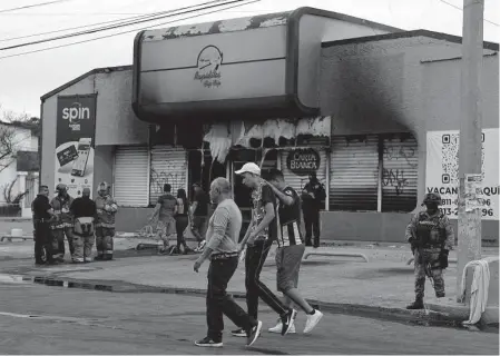  ?? Herika Martinez/AFP/TNS ?? Members of the Mexican army, firefighte­rs and forensic experts work Thursday at a site where shops were burned down in Ciudad Juárez. Four other cities near the U.S.-Mexico border were hit with fiery gang violence Friday, authoritie­s said.