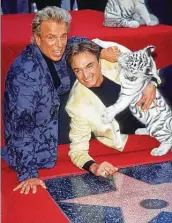  ?? Chris Delmas / AFP via Getty Images ?? Siegfried Fischbache­r, left, and Roy Horn are joined by a tiger during their Walk of Fame ceremony in Hollywood in 1999. Fischbache­r died Wednesday.