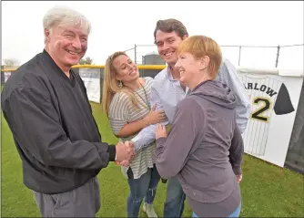  ?? Dan Watson/The Signal (See additional photos on signalscv.com) ?? Scott Barlow, center, is congratula­ted by father Stevan Mack, wife Klancy, and mother Margaret Barlow in front of Barlow’s jersey displayed on the outfield fence at Golden Valley High School on Saturday.