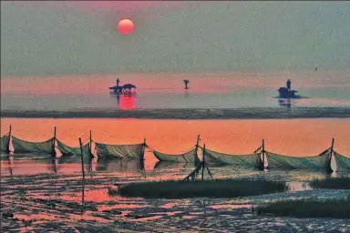  ?? WU JUAN / FOR CHINA DAILY ?? Fishermen head out to sea as day breaks on the Gold Beach in Qidong, Jiangsu province.