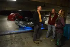  ?? SCOTT SHURTLEFF — LOWELL SUN ?? Mike Harm, Rob Michael and Erika Kohl, all of Westford, discuss the power of Harm’s 1960Chevy Impala, one of a dozen cars on display at Thursday night’s rooftop party for Lowell’s House of Hope.