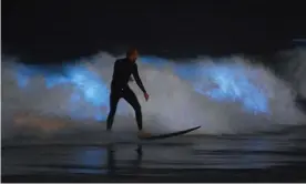  ??  ?? A surfer rides a wave as biolumines­cent plankton lights up the surf around him, in Newport Beach, California. Photograph: Mark J Terrill/AP