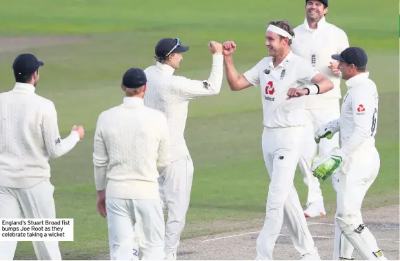  ??  ?? England’s Stuart Broad fist bumps Joe Root as they celebrate taking a wicket