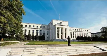  ?? — Reuters ?? Higher rates: A file picture showing a police officer keeping watch in front of the US Federal Reserve building in Washington. The US is poised to raise interest rates three times this year.
