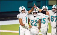  ?? Doug Murray / Associated Press ?? Dolphins quarterbac­k Tua Tagovailoa (1) celebrates his first NFL play with running back Matt Breida (22), guard Ted Karras (67) and running back Lynn Bowden (15) against the Jets on Oct. 18 in Miami Gardens, Fla.