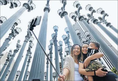  ?? Mel Melcon
Los Angeles Times ?? MARJORIE MABINI, left, takes a photo with her niece Jaydah Mabini, and son Jaren, 1, in front of LACMA’s “Urban Light” installati­on.