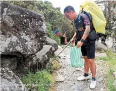  ?? — Pic courtesy of Sabah Parks ?? Keeping clean: a mountain guide collecting rubbish along the trail.