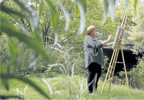  ?? CLIFFORD SKARSTEDT/EXAMINER ?? Cavan Art Academy owner Valerie Kent touches up her artwork on Tuesday next to Cavan Creek in Cavan. The Outdoor Painting Festival in conjunctio­n with Canada Culture Days is happening Saturday and Sunday in Cavan-Monaghan. Artists from across Canada...