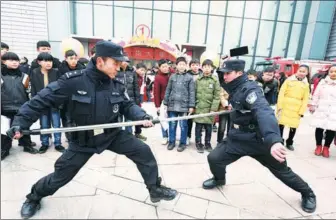  ?? LIU QINLI / FOR CHINA DAILY ?? Police officers showcase defense tactics against a potential blade-wielding suspect outside a shopping mall in Bozhou, Anhui province, on Tuesday. The event was held to encourage the public to report dangerous situations to police and to educate the...