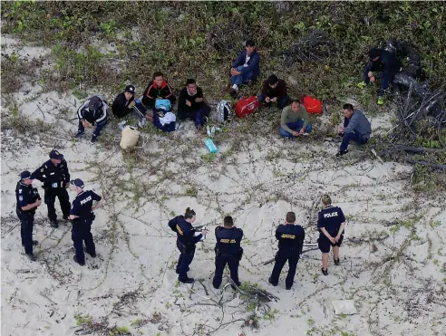  ??  ?? NABBED: Police and Border Force officers guard nine asylum seekers who sunk their fishing boat off Cape Kimberley.