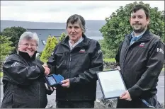  ??  ?? Dr Sam Jones presents the award to Ian Stevens as coxswain David McHaffie looks on.