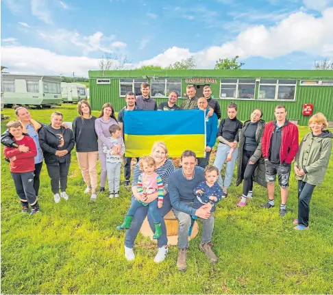  ?? ?? SAFE HAVEN: Farm owners Jennifer and Rowan Marshall with children Munro, 1, and Meryl, 2, alongside some of the refugees from Ukraine at Muirton Farm in Alyth. Picture by Steve MacDougall.