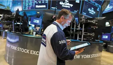  ?? — AFP ?? Downbeat market: Traders work at the New York Stock Exchange. The US benchmark S&P 500 has slumped around 18% from its peak in January.