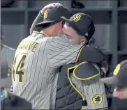  ?? AP ?? Padres starting pitcher Joe Musgrove, left, hugs catcher Victor Caratini in the dugout after pitching a no-hitter against the Texas Rangers on Friday night.