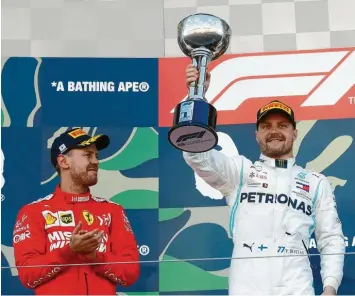  ?? Foto: nordphoto ?? Sebastian Vettel (links) klatscht für Valtteri Bottas. Der Finne hat das Rennen in Japan vor dem deutschen Ferrari-Piloten gewonnen. Auch weil der am Start richtig patzte.