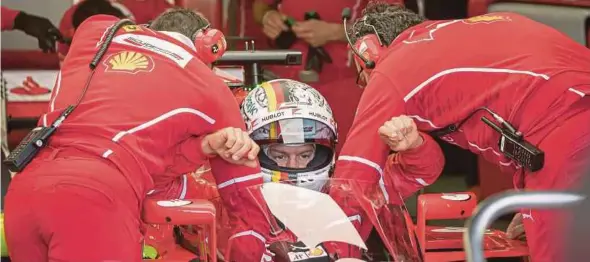  ?? EPA PIC ?? Ferrari driver Sebastian Vettel is assisted into his car during the first practice session of the British Grand Prix yesterday.