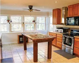  ?? ?? Six windows fill the kitchen with natural light and surround a breakfast room area. Three walls have light maple cabinetry.