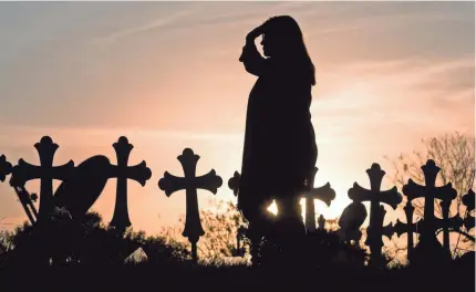  ?? COURTNEY SACCO/USA TODAY NETWORK ?? A woman visits a makeshift memorial Tuesday in Sutherland Springs, Texas, where 26 crosses honor the victims killed at the First Baptist Church. Among those slain was the pastor’s teenage daughter.