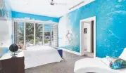  ??  ?? Among its stunning features are a pool with diving board, expansive entertaini­ng areas and a bedroom complete with full-scale surfer mural.