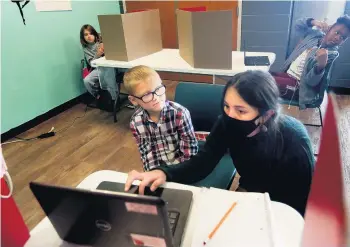  ?? BELOW:
HEATHER ROUSSEAU/ASSOCIATED PRESS PHOTOS ?? ABOVE: Caydan Beckner gets help to log into a virtual class from Stacey Hash-Jans at the Kirk Family YMCA enrichment center in Roanoke. Aydrian Farmer gets help in his reading class from Myesha Logan, a program head.