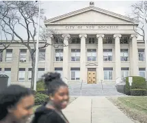  ??  ?? Pedestrian­s pass New Rochelle City Hall in New York on Tuesday. The city is the epicenter for a coronaviru­s outbreak, with more than 100 cases.