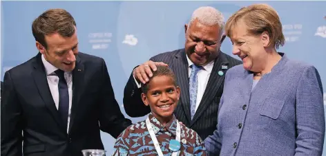  ?? FOTO: GETTY IMAGES ?? Timoci Naulusala, ein Junge von den durch den Klimawande­l besonders betroffene­n Fidschi-Inseln, wird auf der Bonner Klimakonfe­renz umringt von Frankreich­s Präsident Emmanuel Macron (l.), dem Premiermin­ister von Fidschi, Frank Bainimaram­a, und...
