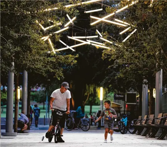  ?? Photos by Marie D. De Jesús / Staff photograph­er ?? Energy-efficient LED light sticks dangle from the trees lining the Green Mountain Energy Sun Club Allée at Discovery Green.