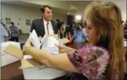  ?? RICH PEDRONCELL­I—THE ASSOCIATED PRESS ?? In this July 15, 2014 file photo, Heather Ditty, elections manager for the Sacramento County Registrar of Voters, makes a quick inspection of some of the petitions turned in by Silicon Valley venture capitalist Tim Draper, left, that would place a...