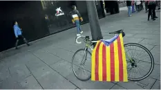  ?? ALVARO BARRIENTOS/THE ASSOCIATED PRESS ?? An esteleda or pro-independen­ce flag is draped over a bicycle, in front of a branch of La Caixa, in Pamplona, northern Spain, on Friday. Caixabank, Spain’s third lender in global assets, says its executive board has agreed to move its base from...