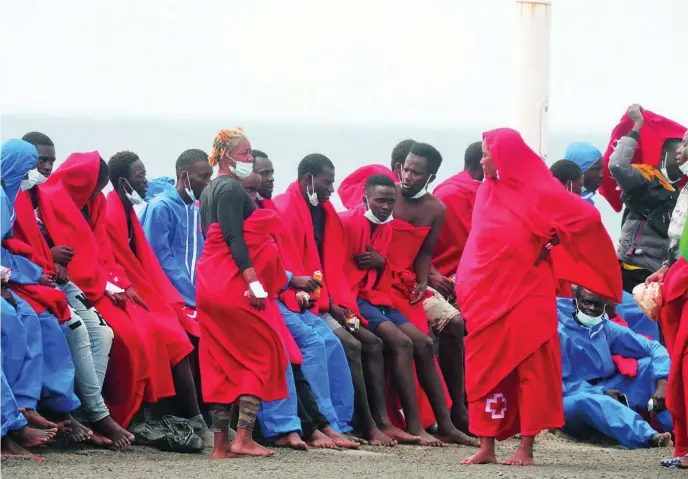  ?? EFE ?? Decenas de inmigrante­s, entre ellos varias mujeres, son atendidos ayer por Cruz Roja tras su rescate en aguas del Atlántico frente a las costas canarias