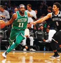  ?? (Reuters) ?? WEARING A mask due to a facial fracture, Boston Celtics guard Kyrie Irving (left) drives to the hoop against Brooklyn Nets defender Spencer Dinwiddie during the Celtics’ 109-102 road victory over the Nets on Tuesday night, Boston’s 13th straight win.