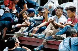  ?? MOISES CASTILLO/AP ?? Honduran migrants traveling to the United States as a group, get a free ride on back of a trailer truck flatbed Wednesday, as they make their way through Teculutan, Guatemala.