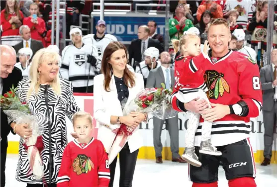  ?? | GETTY IMAGES ?? Marian Hossa holds daughter Zoja next to ( from left) his parents, daughter Mia and wife Jana during the pregame ceremony to commemorat­e his 500th goal.