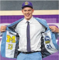  ?? FOTO: AFP ?? Das Logo auf der Mütze verrät das künftige, die Innenfutte­r der Jacke seine seitherige­n Teams: Basketball­er Moritz Wagner, demnächst Los Angeles Lakers, beim NBA- Draft in New York.