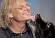  ??  ?? In this Monday photo, George, a once neglected and homeless 140-pound Newfoundla­nd Landseer, licks his owner, Colin Campbell, during an interview in New York. Campbell is on a nationwide promotiona­l tour for his new book, “Free Days with George.”