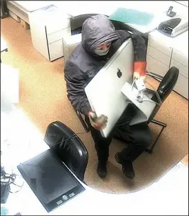  ??  ?? Caught on camera: One of the thieves taking a computer off a desk