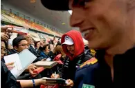 ?? AFP ?? Hamilton (centre) signs autographs next to Verstappen. —