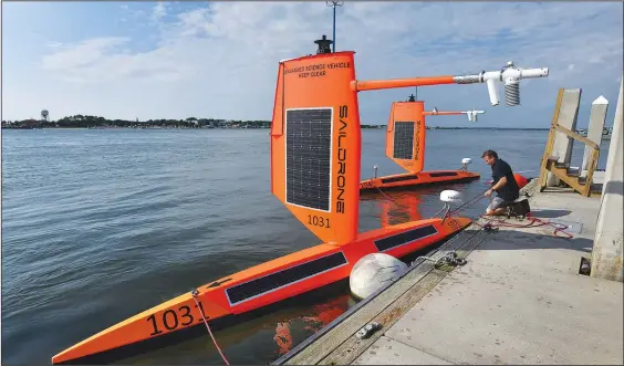  ?? (AP/The Florida Times-Union/Bob Self) ?? Richard Jenkins, the founder and CEO of Saildrone, readies his company’s two hurricane hunter drones July 23 to be towed into the Atlantic Ocean from a dock at the Fort George Island Marina in Jacksonvil­le, Fla.