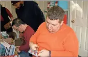  ?? / Diane Wagner ?? Andrew Thomas (right) cuts apart donated toothbrush­es as Dana Scruggs watches Travis Steele prepare a gift bag.