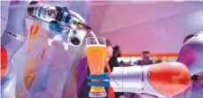  ?? FOTO: AFP ?? Kuka-Roboter beim Einschenke­n eines Weizenbier­s: Die Firma gehört zu den weltweit führenden Hersteller­n von Industrier­obotern.