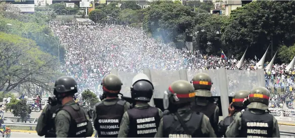  ?? AP ?? Bolivarian National Guards stand on a highway overlookin­g an anti-government march trying to make its way to the National Assembly in Caracas, Venezuela, Wednesday, May 3. Driving the latest outrage is a decree by Venezuelan President Nicolas Maduro to...