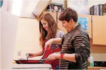  ??  ?? Seventh-graders Lillian Shumay and Jude Lewis learn to cook economical dishes like eggs and grilled cheese in the family and consumer sciences classroom at Choctaw Middle School. Their teacher, Richard Boone, is a retired Air Force senior master...