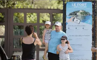  ?? (Photos Franz Chavaroche et Luc Boutria) ?? Macron ou pas, les vacanciers qui viennent plage de Cabasson prennent le temps de faire une photo devant l’entrée du fort de Brégançon, où le couple présidenti­el est en vacances depuis le vendredi  août.