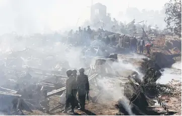  ??  ?? Traders and riot police are seen at the smoulderin­g scene of fire that gutted down the timber dealership of the Gikomba market and nearby homes in central Nairobi, Kenya.