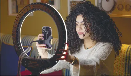  ?? AFP ?? Mariam Ashraf, a teacher and ‘natural hair influencer’, combs her hair during a livestream to her more than 90,000 followers. –