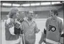  ??  ?? Coach Fred Shero, center, talks with captain Bobby Clarke, left, and goalie Bernie Parent, right, on the first day of practice in 1975. Back then, Clarke had head of envious hair.